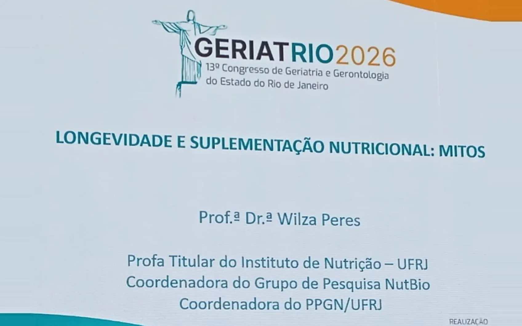 Telão da GeriatRio 2026, 13º Congresso de Geriatria e Gerontologia do Estado do Rio de Janeiro, exibindo a palestra Longevidade e suplementação nutricional: mitos, da Prof.ª Dr.ª Wilza Peres, da UFRJ