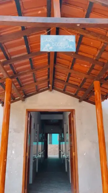 Entrada da casa, com telhado de telhas aparentes e placa escrita Lar Doce Lar