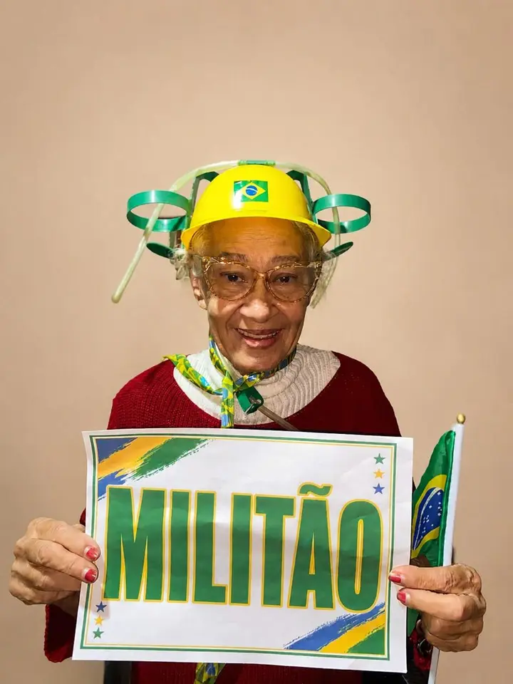 Residente torcendo pelo Brasil na Copa do Mundo 2026, com adereços verde e amarelo e um cartaz com o nome de Militão