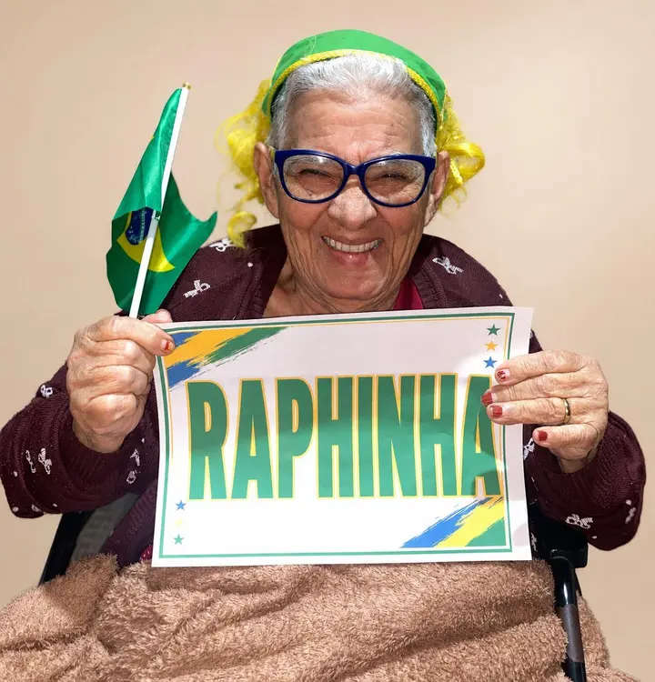 Residente torcendo pelo Brasil na Copa do Mundo 2026, com adereços verde e amarelo e um cartaz com o nome de Raphinha